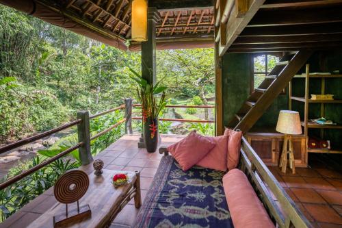 a balcony of a tree house with a couch and a table at Bali Eco Stay in Blimbing