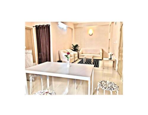 Reef Hotel في شامشاباد: غرفة معيشة مع طاولة وكراسي بيضاء