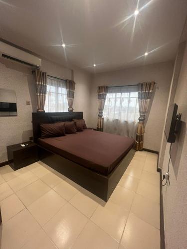 a bedroom with a large bed and two windows at Luxury 2 Bedroom family Apartment in Yaba Lagos in Lagos