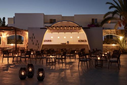 a group of tables and chairs in front of a building at Absolute Kiotari Resort in Kiotari