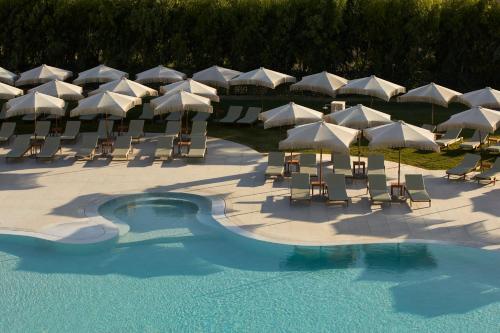 a group of chairs and umbrellas next to a pool at Absolute Kiotari Resort in Kiotari
