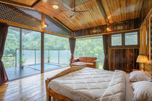 um quarto com uma cama grande e uma janela grande em The Arboreal Resort em Āmbavna