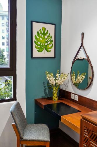 a room with a desk with a chair and a mirror at 22Land Classic Suites in Hanoi