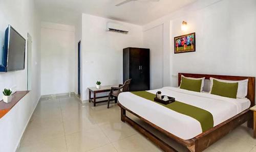 a bedroom with a large bed and a television at FabExpress Aqua Vista in Morjim