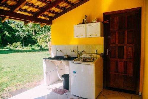 a kitchen with a sink and a refrigerator next to a door at Casa Flor da Serra in Nobres