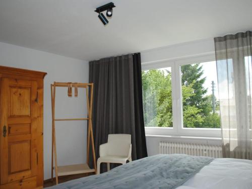 1 dormitorio con 1 cama, 1 silla y 1 ventana en Ferienhaus Joos, en Uhldingen-Mühlhofen