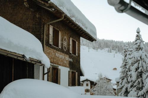 レッヒにあるMargarethe Apartments Lechの雪に覆われた木の隣の建物