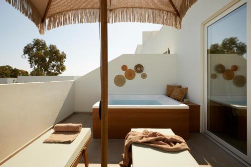 a bathroom with a tub and a table and an umbrella at Absolute Kiotari Resort in Kiotari