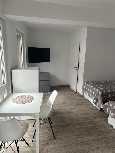 a white room with a bed and a table and chairs at Neckar-Apart in Heilbronn