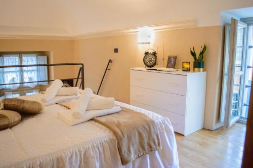 een slaapkamer met een bed met witte lakens en een dressoir bij Esclusivo Loft Centro Storico private garden E-Bike in Cherasco