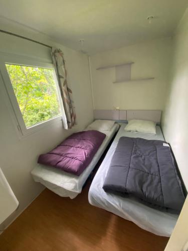 2 Betten in einem kleinen Zimmer mit Fenster in der Unterkunft Camping Val Saint Jean in Mauriac