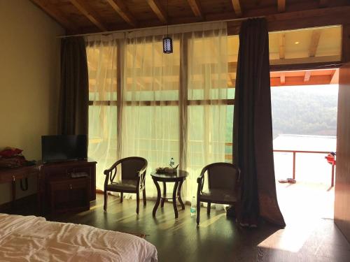 1 dormitorio con 2 sillas, mesa y ventana en Zhingkham Cottages en Thimphu