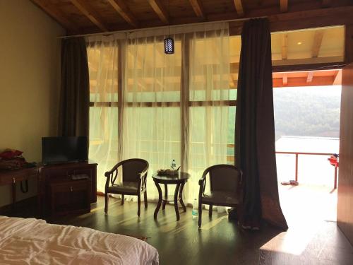 um quarto com 2 cadeiras, uma mesa e uma janela em Zhingkham Cottages em Thimphu