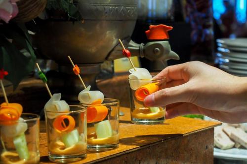 a person is making a drink in four glasses at Bangkok Palace Hotel in Bangkok