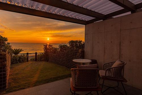 a patio with chairs and a table and a sunset at amane in Kyonan