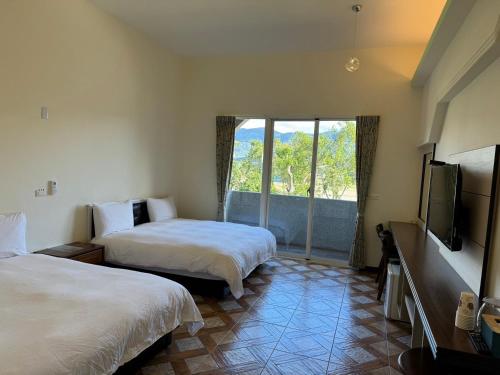 a hotel room with two beds and a flat screen tv at 玟均民宿 Wenjun 台東縣民宿1277號 in Chishang