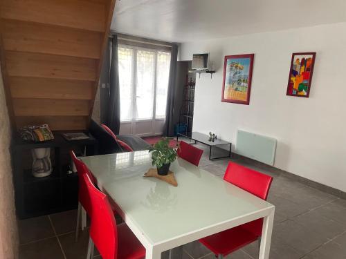 une salle à manger avec une table blanche et des chaises rouges dans l'établissement Les Gîtes de La Vieille Roue - Gite 3, à Reignac