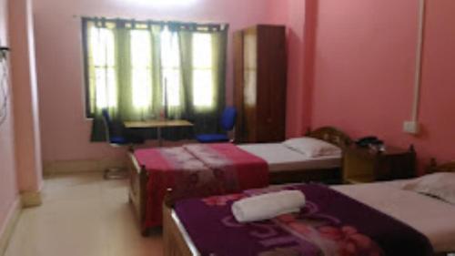 Habitación con 2 camas y ventana en una habitación en Sewak Lodge Silchar, en Silchar
