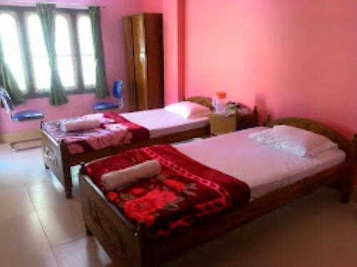 Sewak Lodge Silchar في سيلكار: سريرين في غرفة بجدران وردية