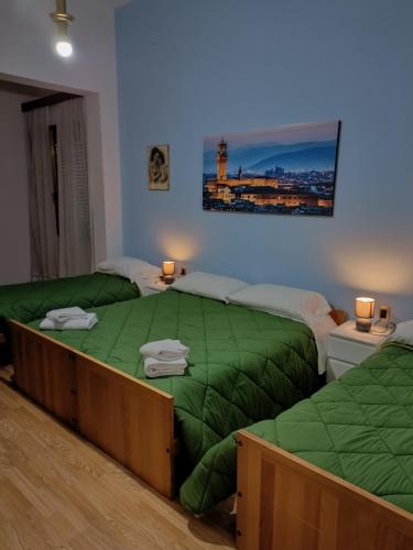 a bedroom with two beds with green sheets and lamps at Hotel Alba Serravalle in Serravalle Pistoiese
