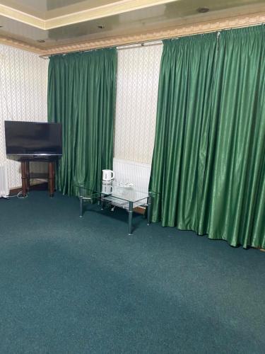 a living room with green curtains and a piano at Відпочинковий комплекс,міні готель Старий дворик in Lviv