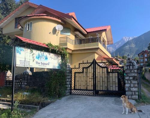 un perro sentado frente a una casa con una puerta en The Sojourn en Dharamshala