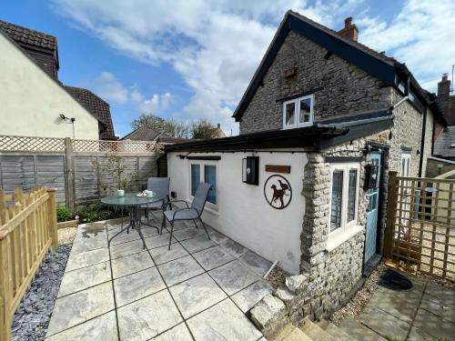 a patio with a table and chairs in front of a house at The Dog House, Mere in Mere