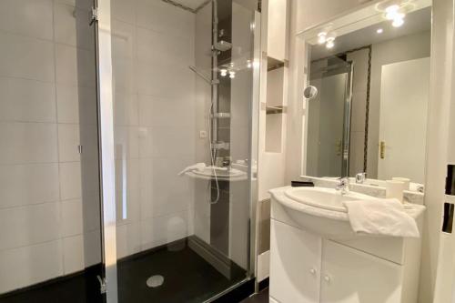 une salle de bain blanche avec un lavabo et une douche dans l'établissement Maison 4 personnes avec jardin et parking, au Crotoy