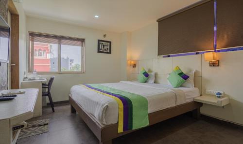a hotel room with a bed and a desk and a window at Hotel Casa, Vadodara in Vadodara