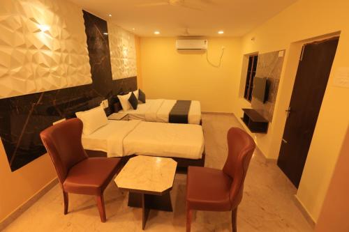 ein Hotelzimmer mit einem Bett und einem Tisch und Stühlen in der Unterkunft Kailasaa Residency in Tiruvannāmalai