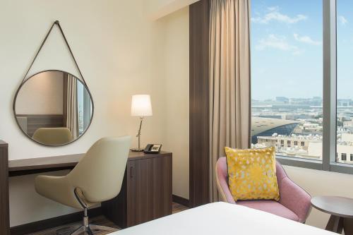 a hotel room with a mirror and a chair at Hampton By Hilton Dubai Airport in Dubai