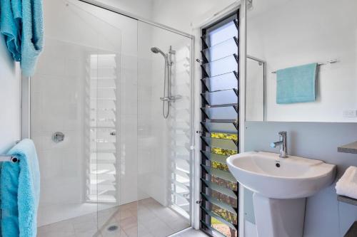 uma casa de banho branca com um chuveiro e um lavatório. em Ohana Kioloa em Kioloa
