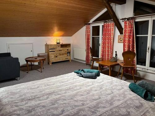 a bedroom with a large bed and a desk and windows at Chalet Maithili Lauterbrunnen -152-Year-Old Majestic Chalet in Lauterbrunnen