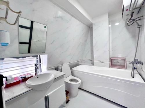 y baño con bañera blanca, aseo y lavamanos. en Daisy homestay & apartment en Hai Phong