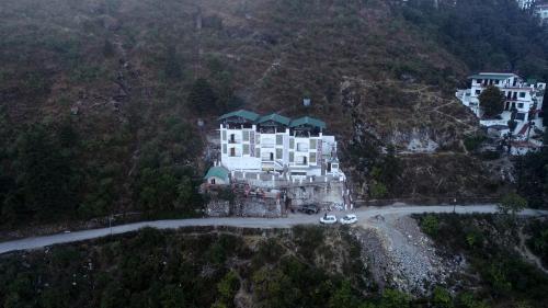 a large white building on the side of a mountain at The Whispering Pine and Suites in Mussoorie