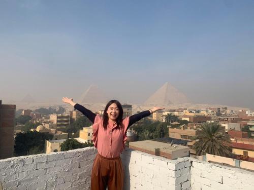 a woman standing on top of a wall with the pyramids at Eyad Pyramids view in Cairo