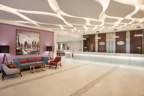 a lobby with a couch and chairs in a room at Hampton By Hilton Dubai Airport in Dubai