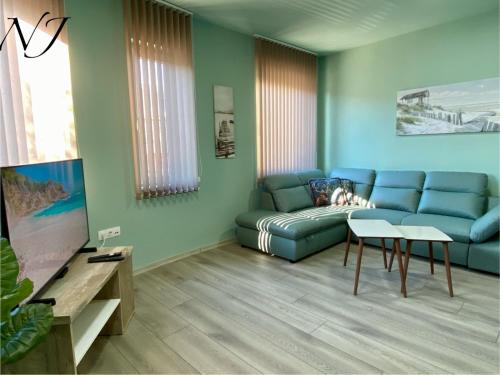a living room with a blue couch and a tv at NJ Luxury rooms and suites in Varna City