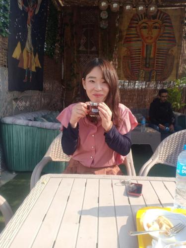 a woman sitting at a table taking a picture with a camera at Eyad Pyramids view in Cairo