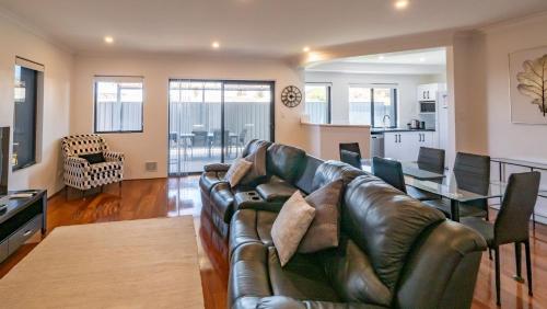 a living room with a leather couch and a table at Hollow Beach House - Bunbury in Bunbury