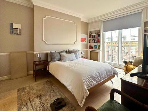 a bedroom with a large bed and a large window at Spacious and beautiful flat in Mayfair, Berkeley St in London
