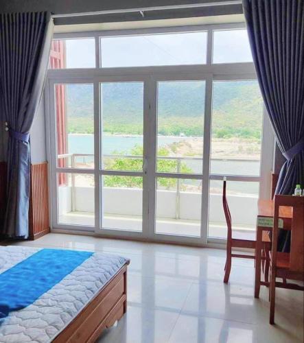a bedroom with a large window and a bed and a table at Khu du lịch Hang Rái - Ninh Thuận in Thôn Thái An