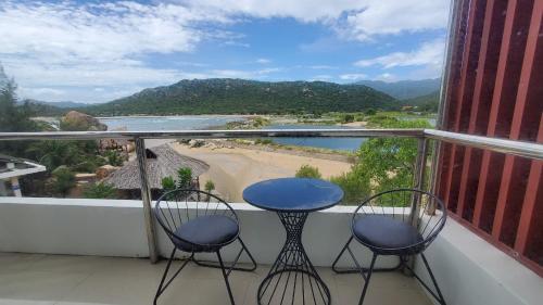 a balcony with two chairs and a table and a view of a beach at Khu du lịch Hang Rái - Ninh Thuận in Thôn Thái An