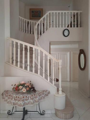 a white staircase with a chair and a clock at The Sangtus Home in Babakan Madang