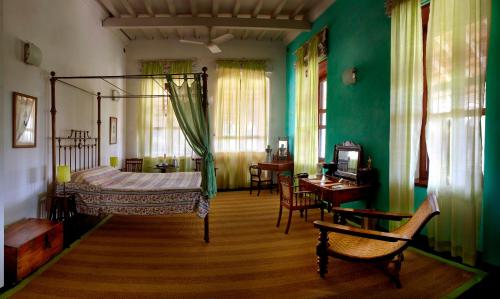 a bedroom with a bed and a table and chairs at Neemrana's - Bungalow on The Beach in Tarangambādi