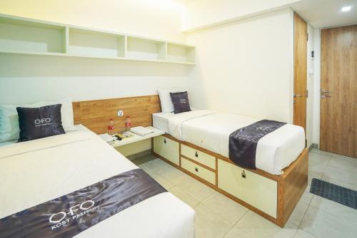Pare的住宿－OFO Kost Premium Kampung Inggris Pare Syariah Mitra RedDoorz，一间卧室配有两张床和一张桌子,床上铺有四柱床。