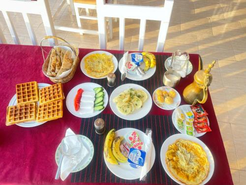 een tafel met borden eten op een rode tafel bij Younis family home in Luxor