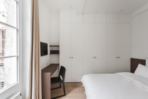 une chambre avec un lit, un bureau et une fenêtre dans l'établissement Adresse Prestigieuse: Appartement Luxueux Marais, à Paris
