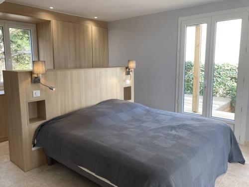 a bedroom with a large bed in a room with windows at Villa de grand standing les Garrigues in Narbonne-Plage