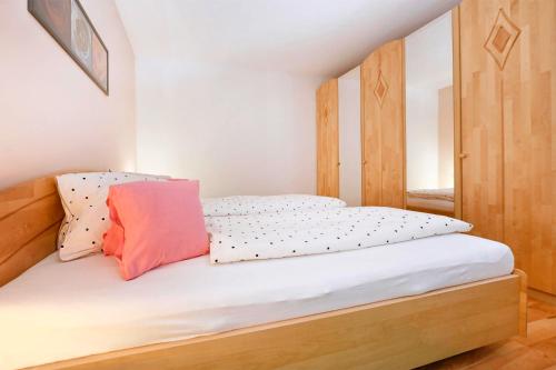 a bedroom with a bed with white sheets and a pink pillow at Chalet Keßler in Tschagguns